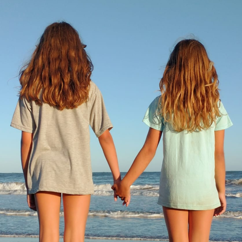 Dos niñas tomadas de la mano frente al mar